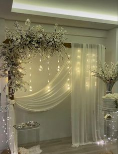 a white wedding ceremony setup with flowers and lights on the wall, draped drapes