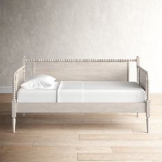 a white daybed sitting on top of a hard wood floor next to a wall