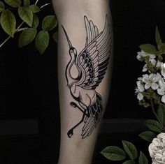 a black and white tattoo on the leg of a person with flowers in the background