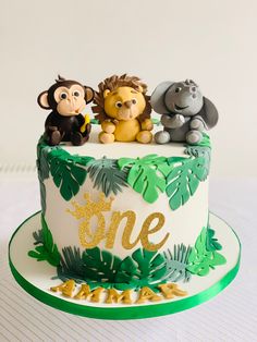 a birthday cake decorated with jungle animals and the number one on it's top