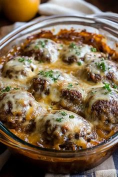 a glass casserole dish filled with meatballs and cheese covered in gravy