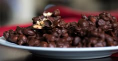 a white plate topped with lots of chocolate covered food next to a red table cloth