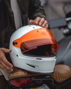 the helmet is being held up by someone's hand while sitting on a motorcycle