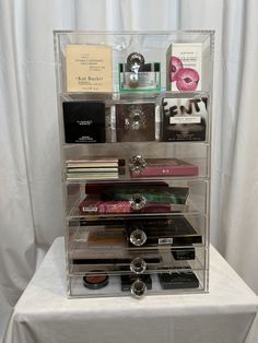 an acrylic display case with various items on it, including perfumes and books