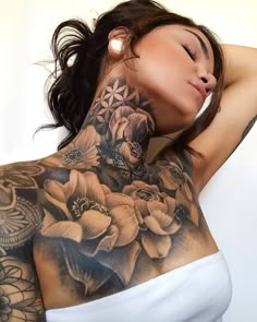 a woman with tattoos on her back and shoulder is posing for the camera while holding her hand behind her head