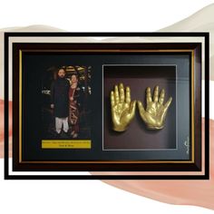 two gold hands are in a shadow box and one is holding the other's hand