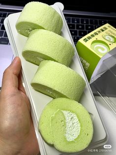 a person holding a tray with some green food in front of a laptop computer on a desk