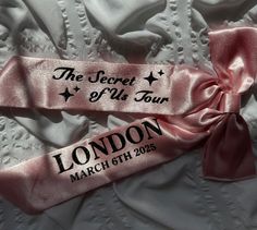 two pink satin ribbons with the names of london and the secret of bus tour written on them