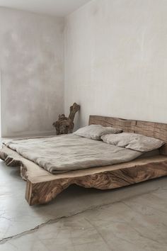 a bed made out of wood in a room with concrete flooring and white walls