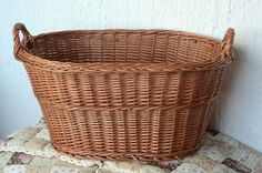 a brown wicker basket sitting on top of a bed next to a white wall