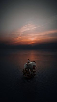 a boat floating on top of a body of water under a cloudy sky at sunset