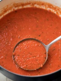 a ladle full of tomato sauce in a pot