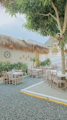 an outdoor dining area with tables, chairs and thatched umbrellas on the roof