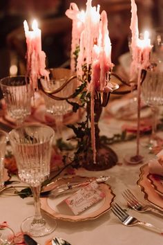 the table is set with pink candles and place settings for two people to sit at