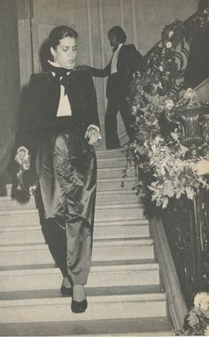 an old black and white photo of two men walking down the stairs in formal attire