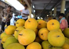 a pile of yellow fruit sitting on top of a wooden table next to people in the background