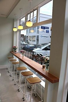 an empty restaurant with lots of stools and tables in front of large windows looking out onto the street