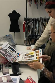 two women sitting at a table looking through magazines