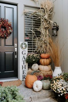 pumpkins and gourds are stacked on the front porch for fall decorating