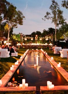 an outdoor dining area with candles lit up on the water and tables set for dinner