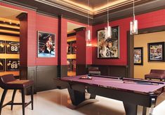 a billiard table in a room with red walls and lights hanging from the ceiling