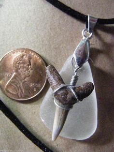 a penny is sitting next to a necklace with a knife on it