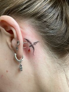 a woman's ear with a small dragon tattoo on it