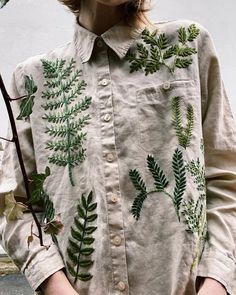 a woman wearing a white shirt with green leaves on it