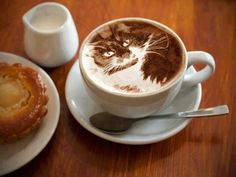 there is a coffee cup with a bear drawn on it next to a plate with a pastry