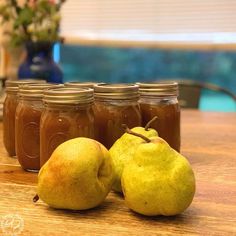 pears and honey sit on a table next to jars with water in the background