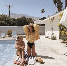 two women sitting on the edge of a swimming pool