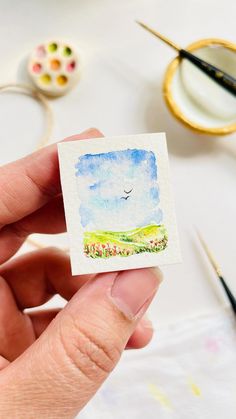 a person holding up a small card with a bird flying over the field on it