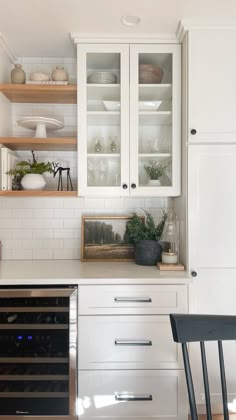 a kitchen with white cabinets and black chairs