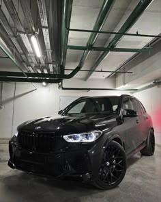 a black bmw suv parked in a parking garage