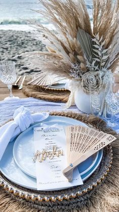 a table set with plates and napkins on the beach