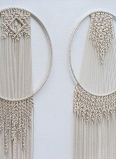 two white wall hangings made out of macrament beads and rope with circular rings