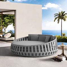 an outdoor living room with a circular couch and large glass doors leading to the ocean