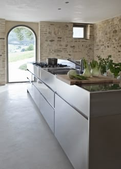 a kitchen with stone walls and an arched doorway leading to the outside area is shown