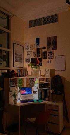 a desk with a laptop computer sitting on top of it next to a wall covered in pictures