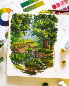 an artist's work with watercolors and paintbrushes on the table