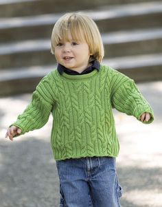 a little boy in a green sweater and jeans