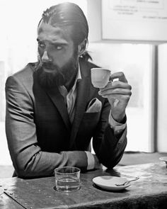 a man sitting at a table drinking from a cup