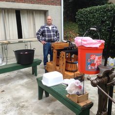 a man standing next to a green table with some buckets on top of it