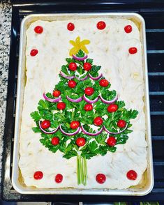 a christmas tree decorated with red berries and green leaves on a baking sheet in an oven