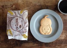 a plate with a cookie shaped like a cat next to a cup of coffee