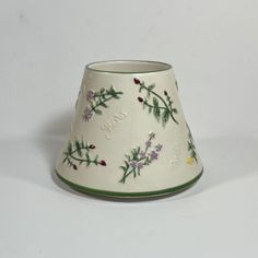 a small white vase with flowers painted on the side and green trim around the bottom