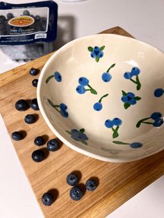 a bowl with blueberries in it sitting on a cutting board