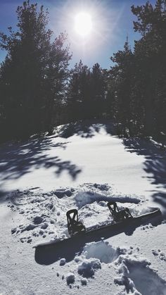 a snowboard laying in the snow on top of a hill next to some trees