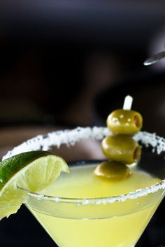 a martini with olives and a lime slice on the rim