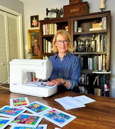 a woman is using a sewing machine to sew some pictures on the table next to her